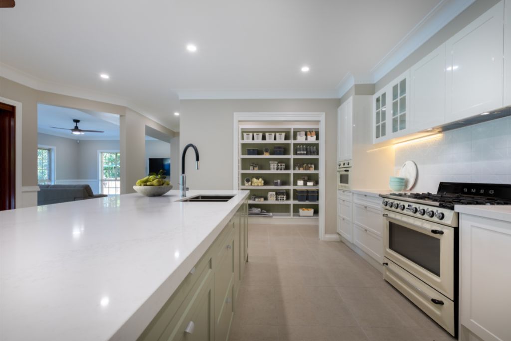 A sleek white kitchen with a large open pantry. | Featured image for Renovare Moreton Bay.